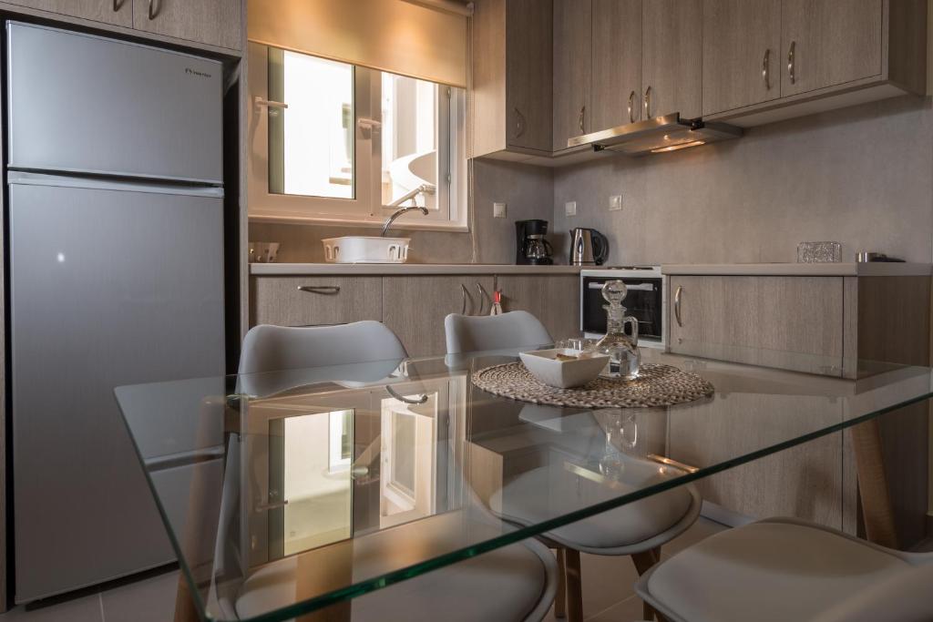 パレオコラにあるAnDi's Apartment's Paleochoraのキッチン(ガラステーブル、白い椅子付)