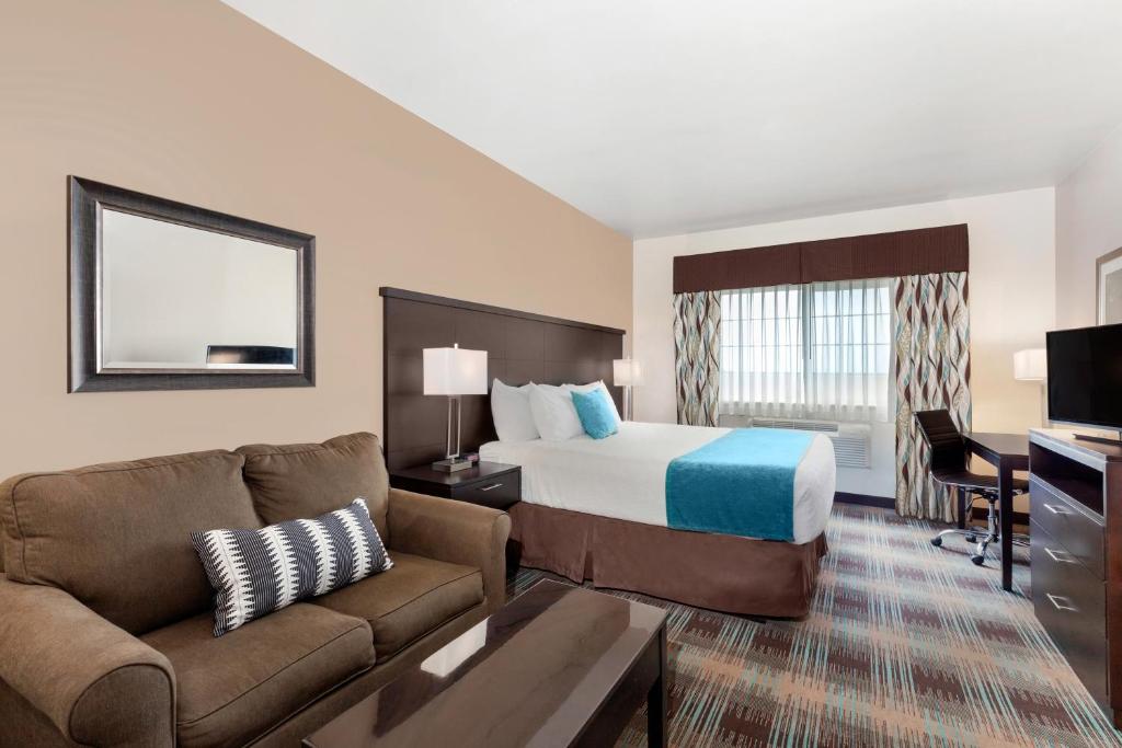 a hotel room with a bed and a couch at Inn at Moses Lake in Moses Lake