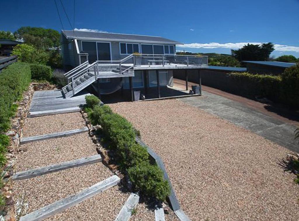 ein Haus mit einer Terrasse und einer Treppe davor in der Unterkunft Bayview Retreat in Oneroa