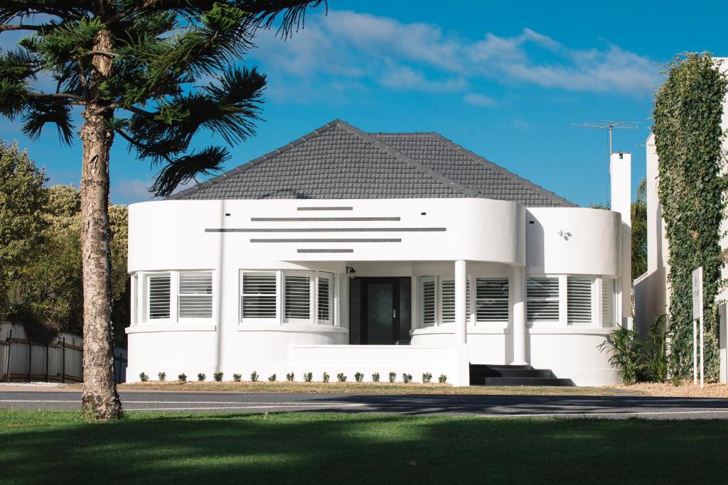 a white house with a palm tree in front of it at Deco Beach Luxury Apartments in Port Lincoln