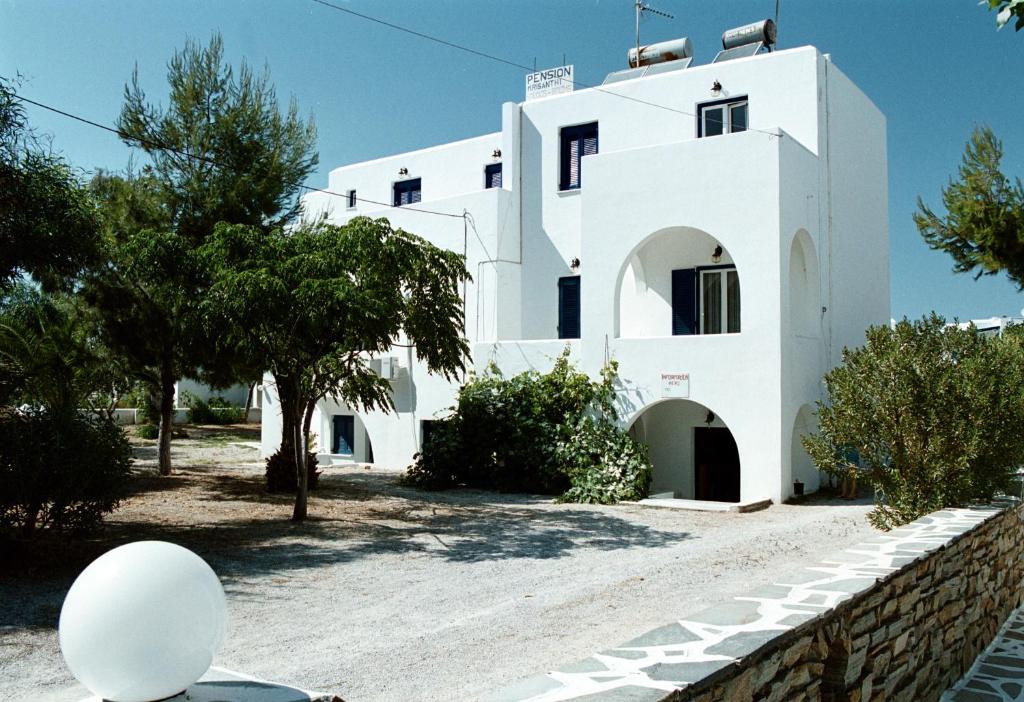 a white house with trees in front of it at Chrisanthi Studios in Agios Prokopios