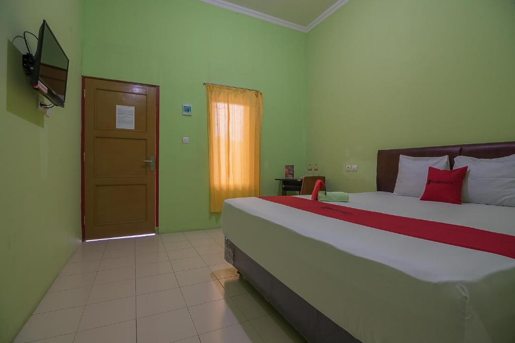 1 dormitorio con 1 cama grande y puerta en RedDoorz near Kampus UMP Purwokerto, en Purwokerto