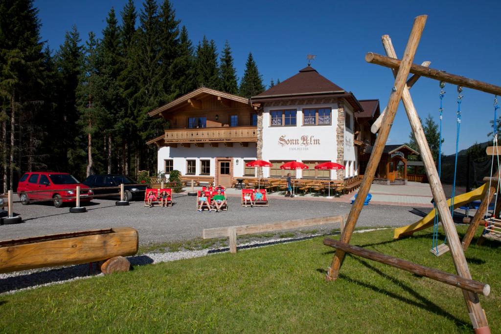 un edificio con un parque infantil con sillas rojas delante de él en Sonnalm, en Altenmarkt im Pongau