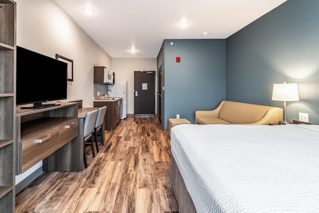 WhitestownにあるWoodSpring Suites Indianapolis Zionsvilleのベッド1台、薄型テレビが備わるホテルルームです。