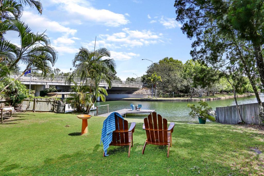 two chairs sitting on the grass next to a river at Clouds End in Noosaville