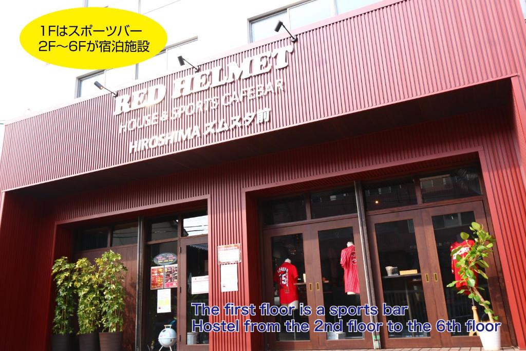 廣島的住宿－RED HELMET House & Sports Bar Hiroshima，红色的建筑,上面有一层的标志,是体育运动的标志