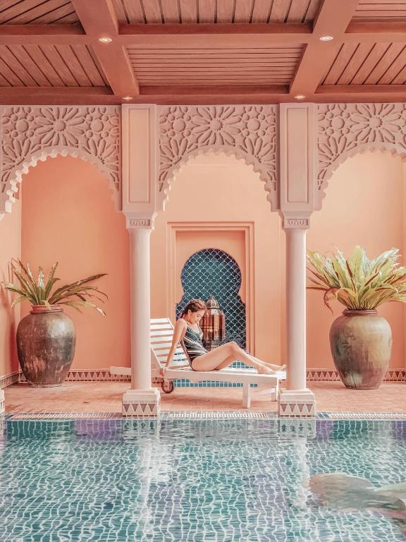 a woman sitting on a bench next to a swimming pool at Kenting Amanda Hotel in Nanwan