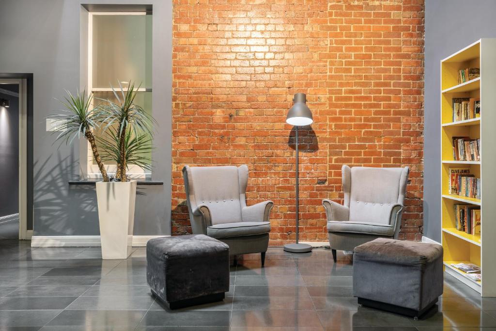 a room with two chairs and a brick wall at Best Western Melbourne City in Melbourne