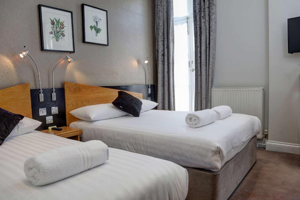 a hotel room with two beds with towels on them at Best Western Buckingham Palace Rd in London