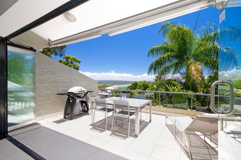 an outdoor patio with a table and chairs on a balcony at A Little Cove treasure, Noosa Heads in Noosa Heads