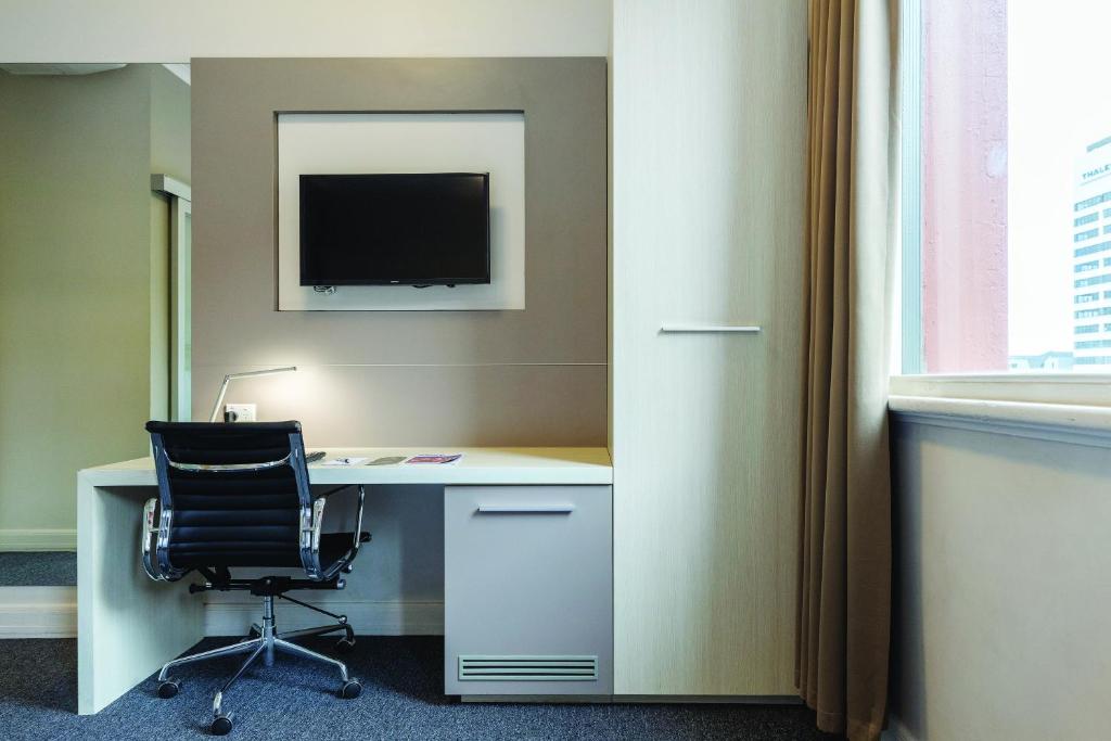 an office with a desk with a chair and a television at Best Western Melbourne City in Melbourne