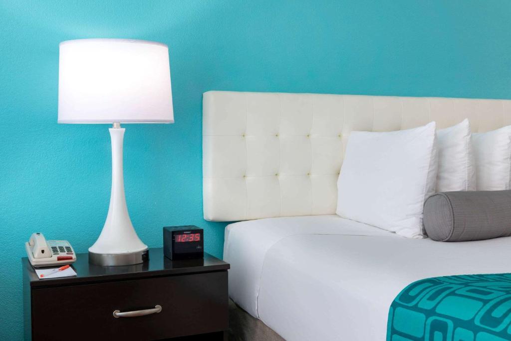 a bed with a lamp and a clock on a night stand at Howard Johnson by Wyndham Rock Hill in Rock Hill