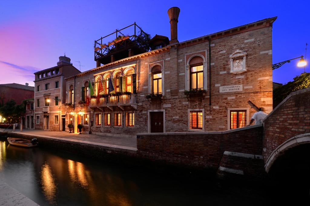 un grande edificio in mattoni accanto a un fiume di notte di Palazzetto Madonna a Venezia