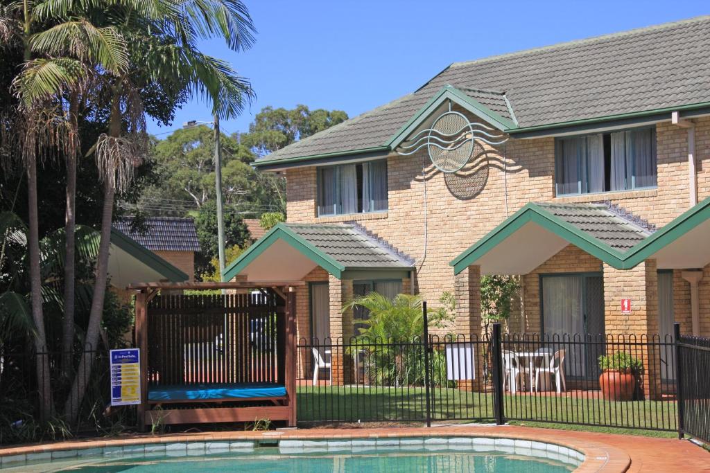 una casa con piscina frente a ella en Aqua Villa Holiday Apartments, en Coffs Harbour