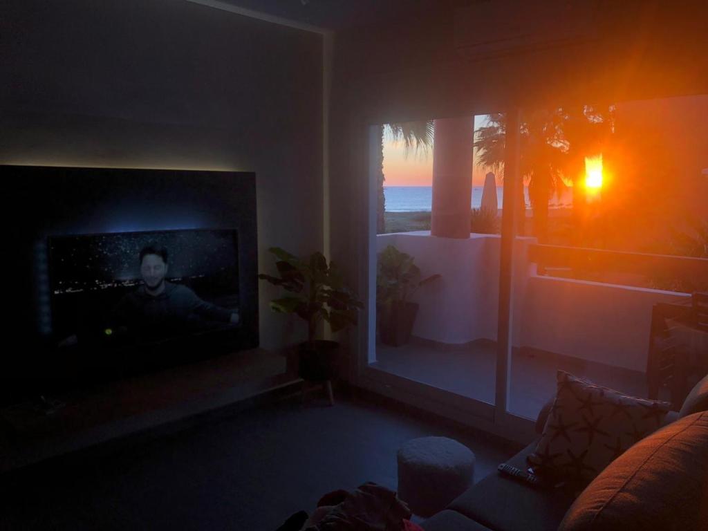 a living room with a flat screen tv and a window at Apartasuites Royal Zahara, Máximo confort con vistas al mar in Zahara de los Atunes