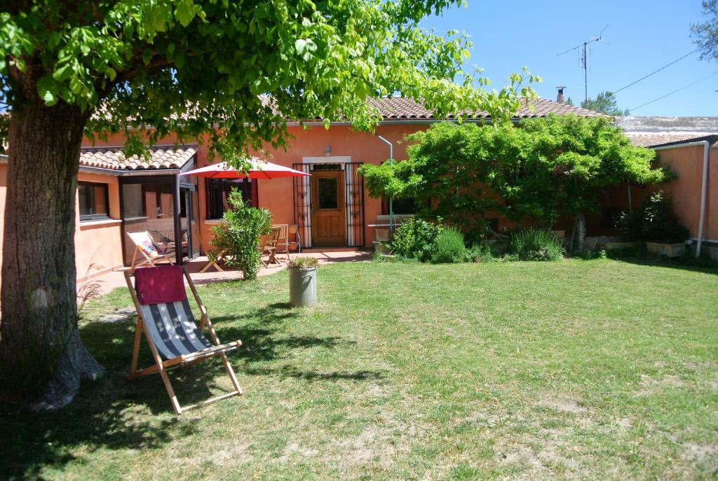 a chair sitting in a yard next to a tree at L'isle verte in LʼIsle-sur-la-Sorgue