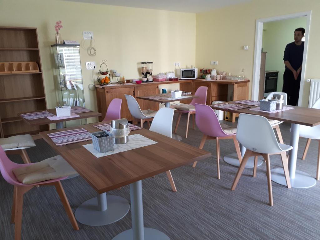 a room with tables and chairs and a man in a kitchen at Guest House Tara in Moravske Toplice