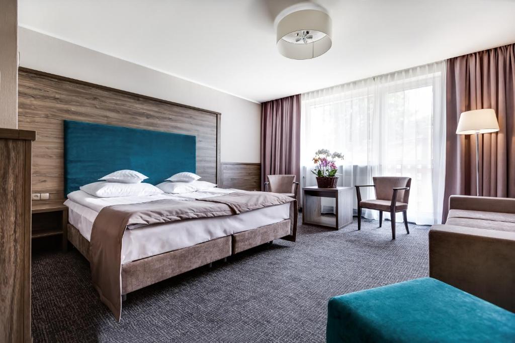 a hotel room with two beds and a chair at Hotel Konradówka Wellness & SPA - 300 metrów do centrum in Karpacz