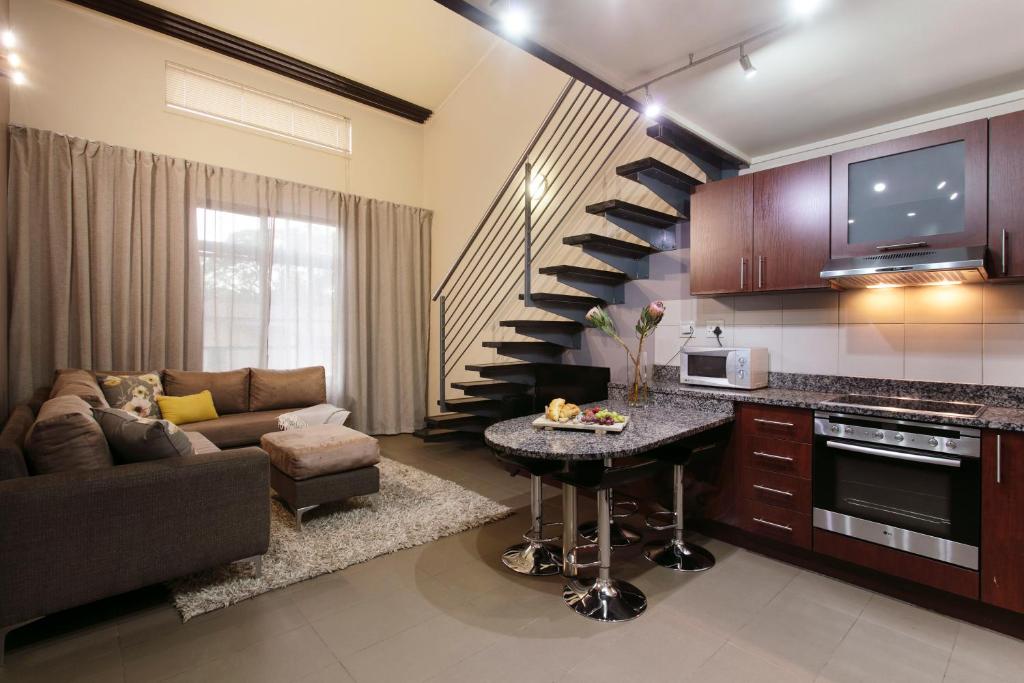 a kitchen and living room with a couch and a staircase at Absolute Farenden Apartments in Pretoria