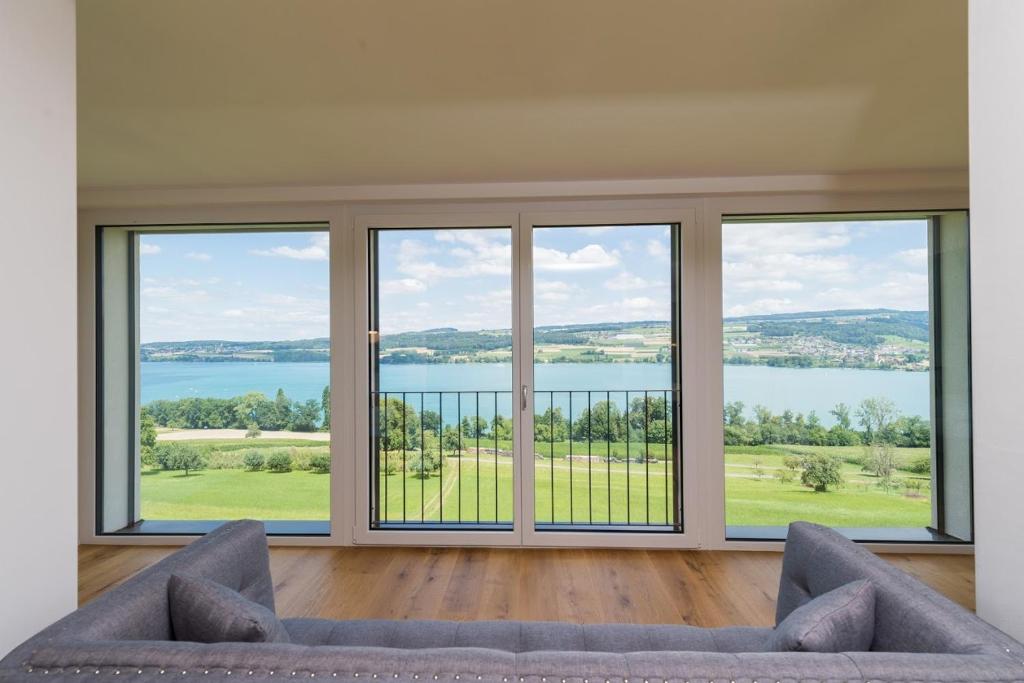 a living room with a couch and large windows at Lake View Apartments Beinwil am See (30 km to Lucerne) in Beinwil