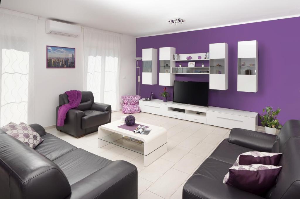 een paarse woonkamer met een bank en een tv bij RAINBOW in Pula
