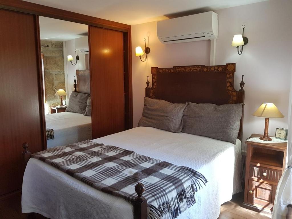 a bedroom with a large bed and a mirror at A Casinha do Beco in Gouveia