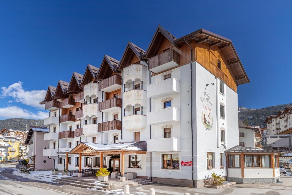 a large white building with a wooden roof at Hotel Rosa Alpina in Andalo