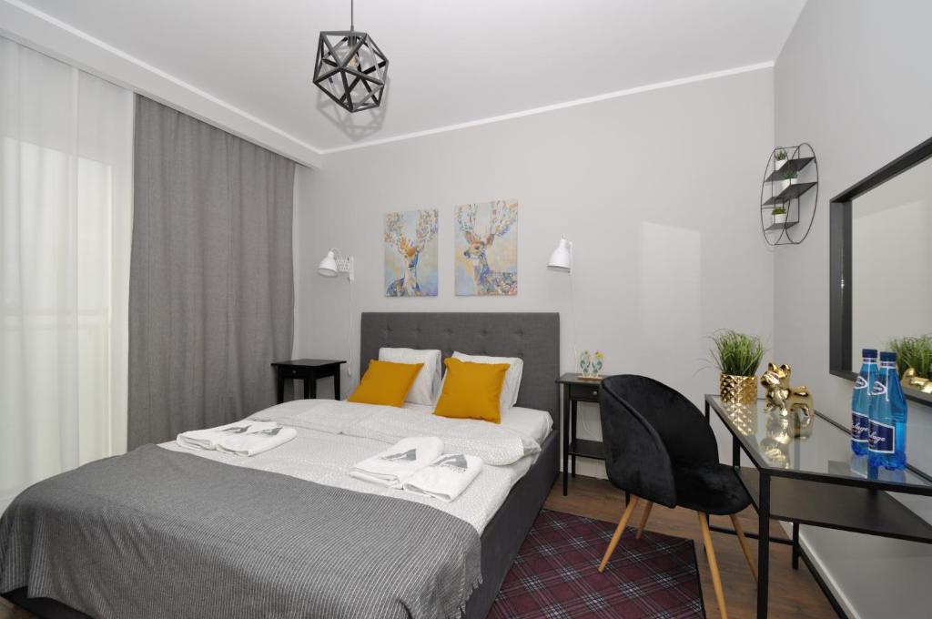 1 dormitorio con cama con almohadas amarillas y escritorio en Apartament RESORT Chełmońskiego Śrem, en Śrem