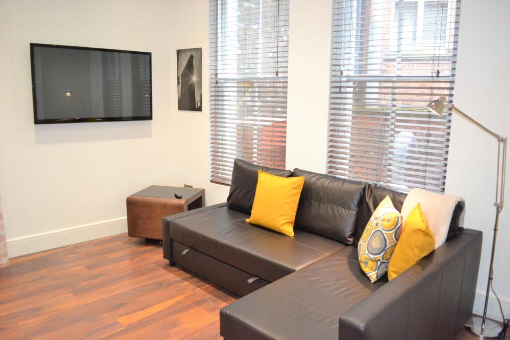 OnPoint - 2 Bed Apartment City Centre Ideal Location! في نوتينغهام: غرفة معيشة مع أريكة وتلفزيون بشاشة مسطحة