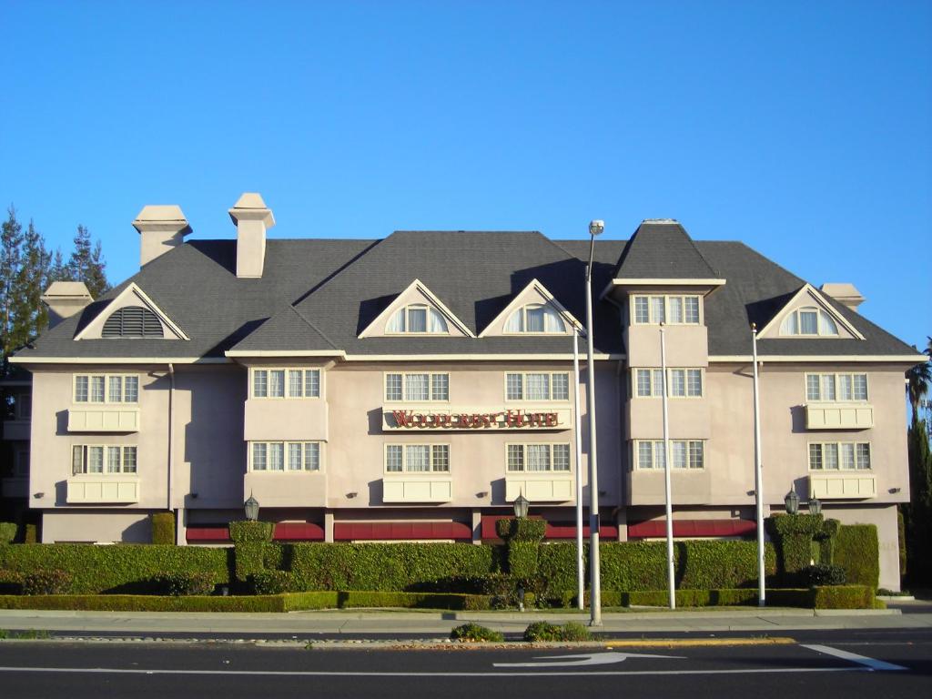 a large white building with a black roof at Woodcrest Hotel in Santa Clara