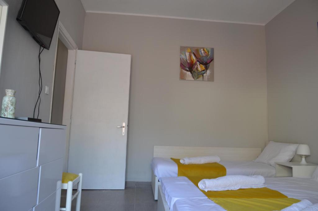 a white room with two beds and a tv at Daisy Apartment in Asprovalta