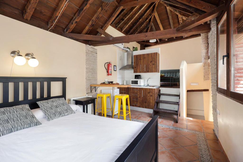 a bedroom with a bed and a kitchen with yellow chairs at Urban Suites Granada in Granada