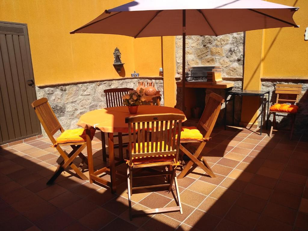 einen Tisch und Stühle mit Sonnenschirm auf einer Terrasse in der Unterkunft Casa Rural El Abuelo Anselmo in Segovia