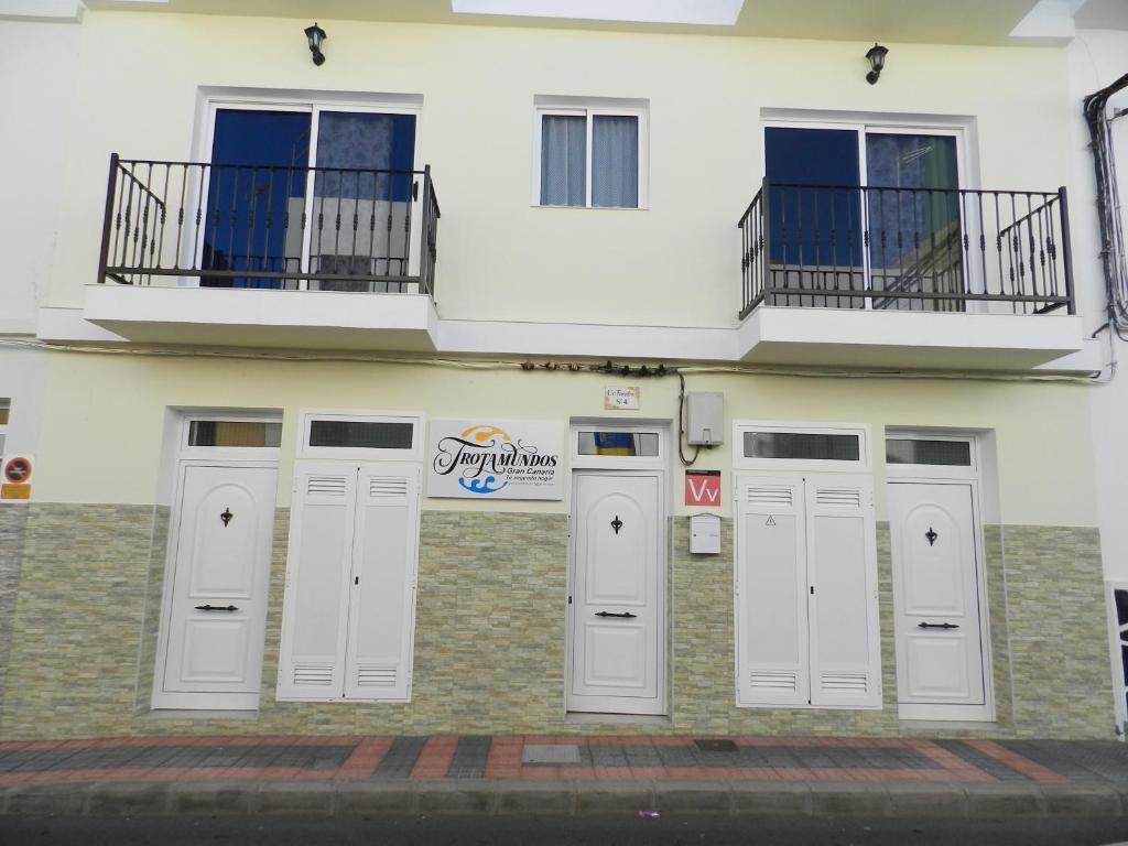 a white building with three doors and a balcony at Trotamundos GC FAMILIAS Y ADULTOS RESPONSABLES in El Tablero