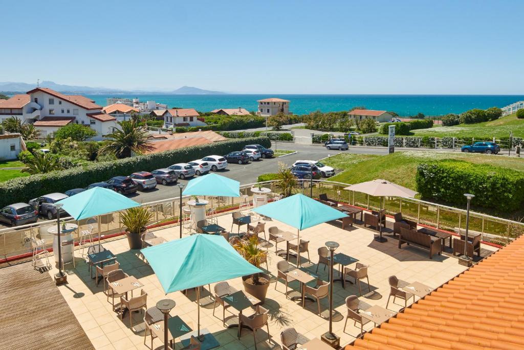 an outdoor patio with blue umbrellas and a parking lot at Hôtel Le Biarritz in Biarritz
