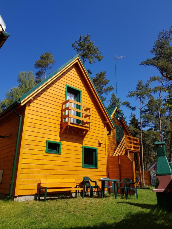 a yellow house with tables and chairs in front of it at Zielone Domki in Pobierowo