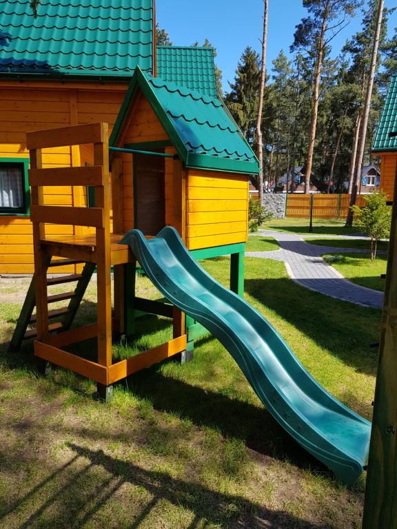 a playground with a slide and a house at Zielone Domki in Pobierowo