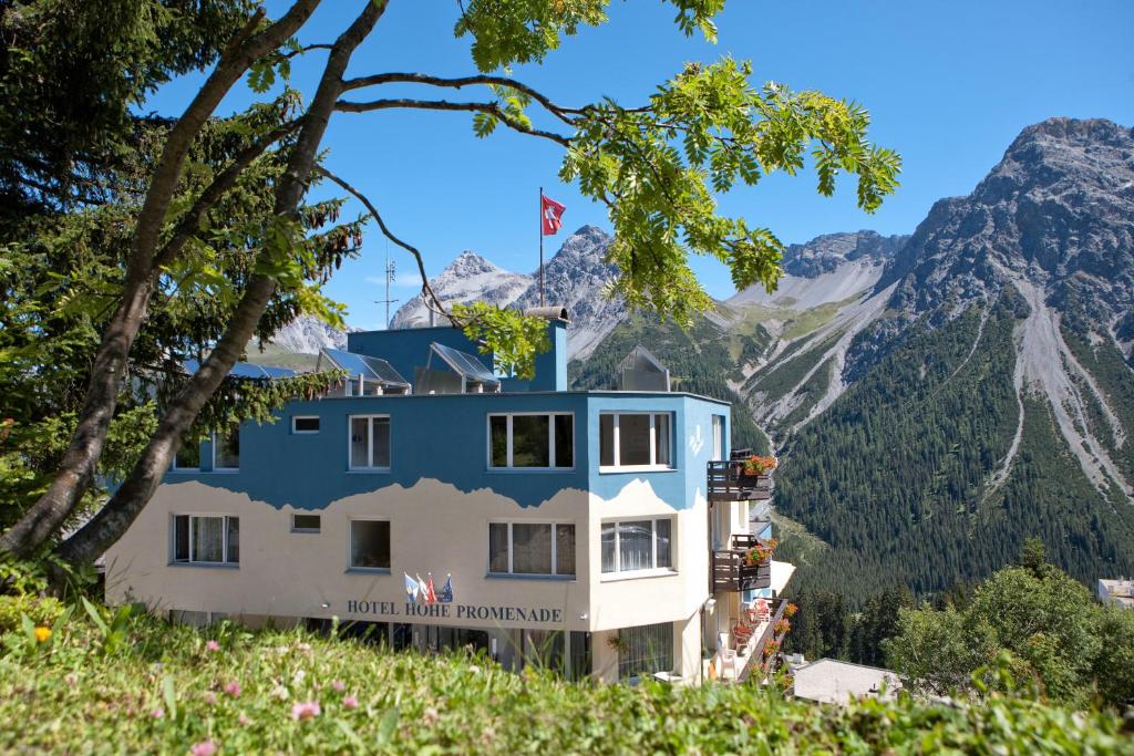 un edificio en una colina con montañas en el fondo en Hotel Hohe Promenade en Arosa