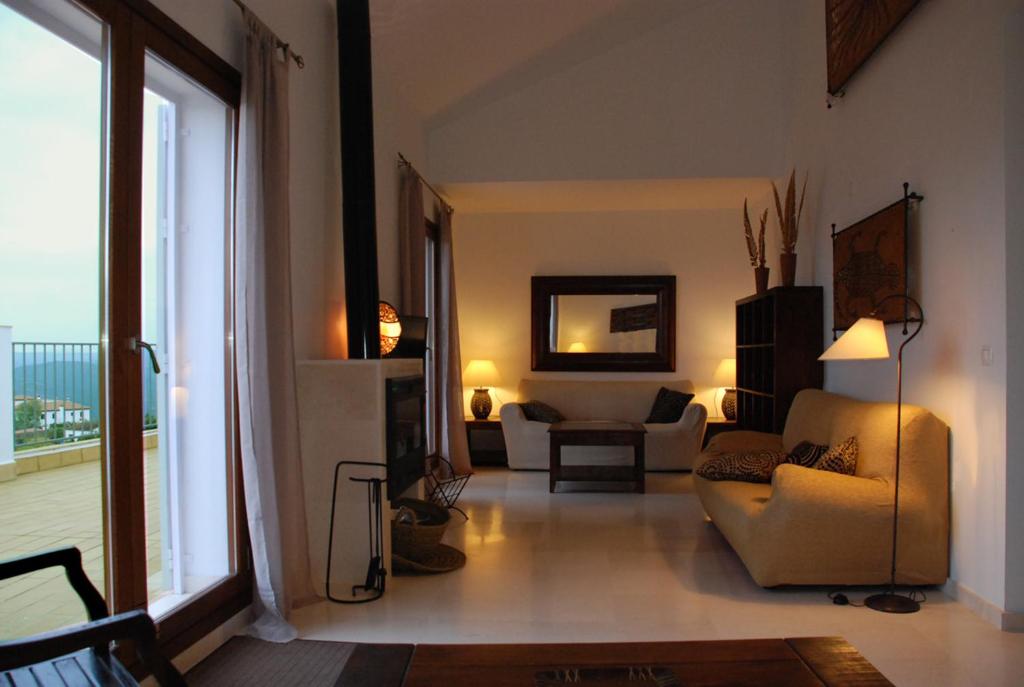 uma sala de estar com um sofá e um quarto com uma janela em Arriba y abajo em Zufre