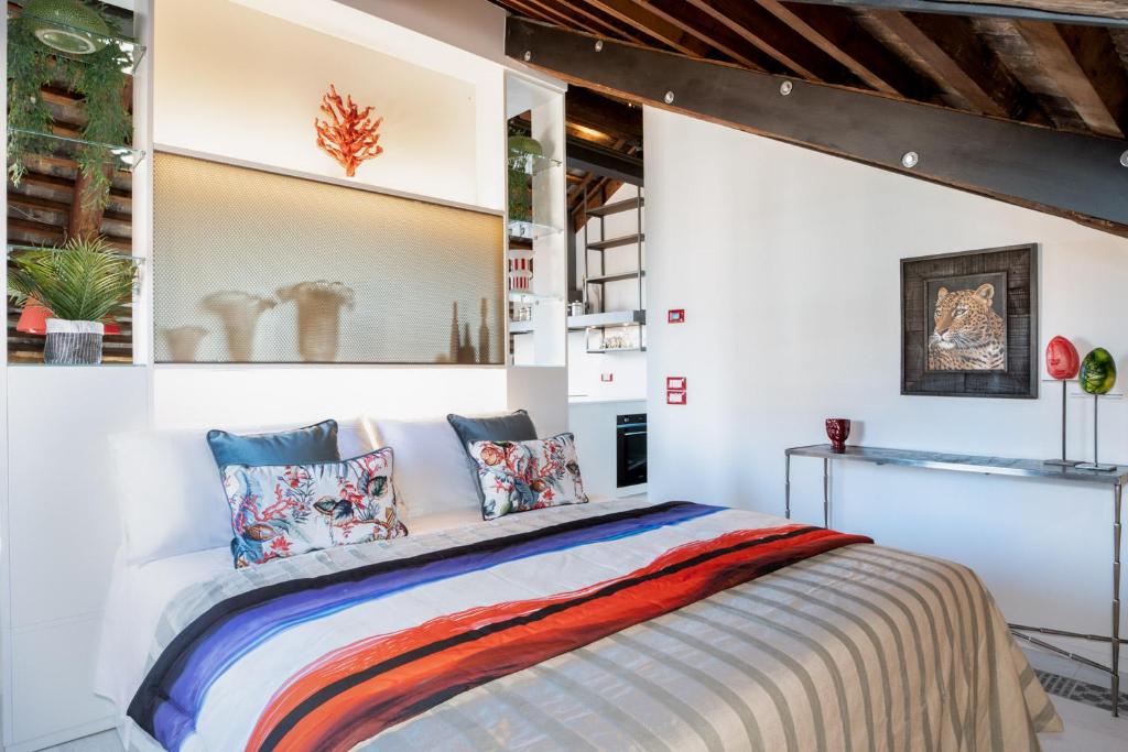 Pgrhome Luxury Apartments Coral Loft Venice في البندقية: غرفة نوم مع سرير مع وسائد ملونة