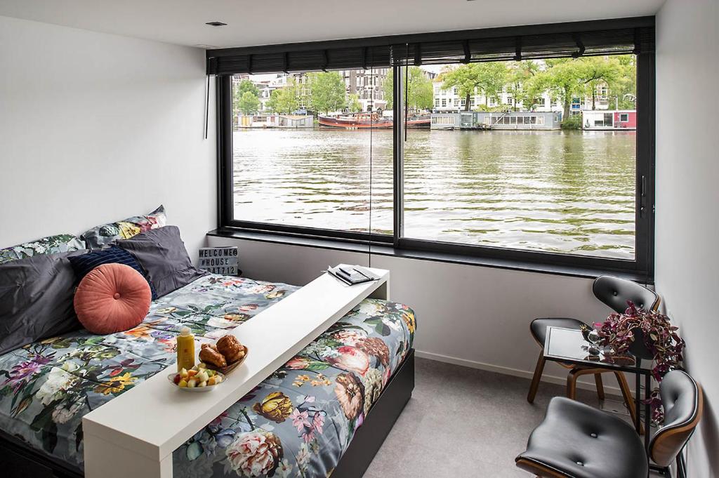 a bedroom with a view of a river from a window at Houseboat Amsterdam - Room with a view in Amsterdam