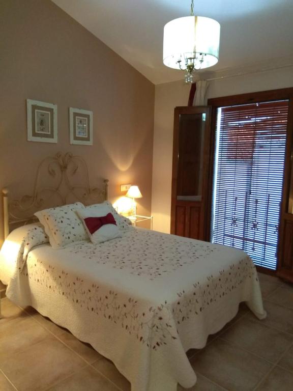 ein Schlafzimmer mit einem weißen Bett und einem Fenster in der Unterkunft Apartamentos Rurales Tía María in Mata de Alcántara