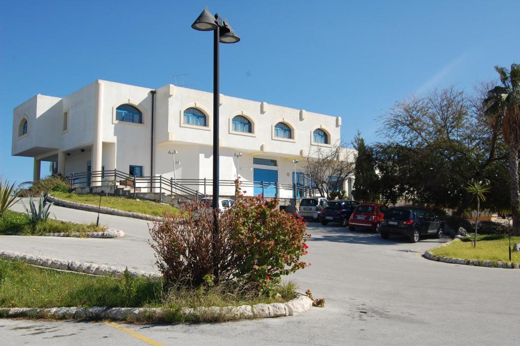 Marina di MelilliにあるHotel Club Pegasoの駐車場車が停まった白い建物