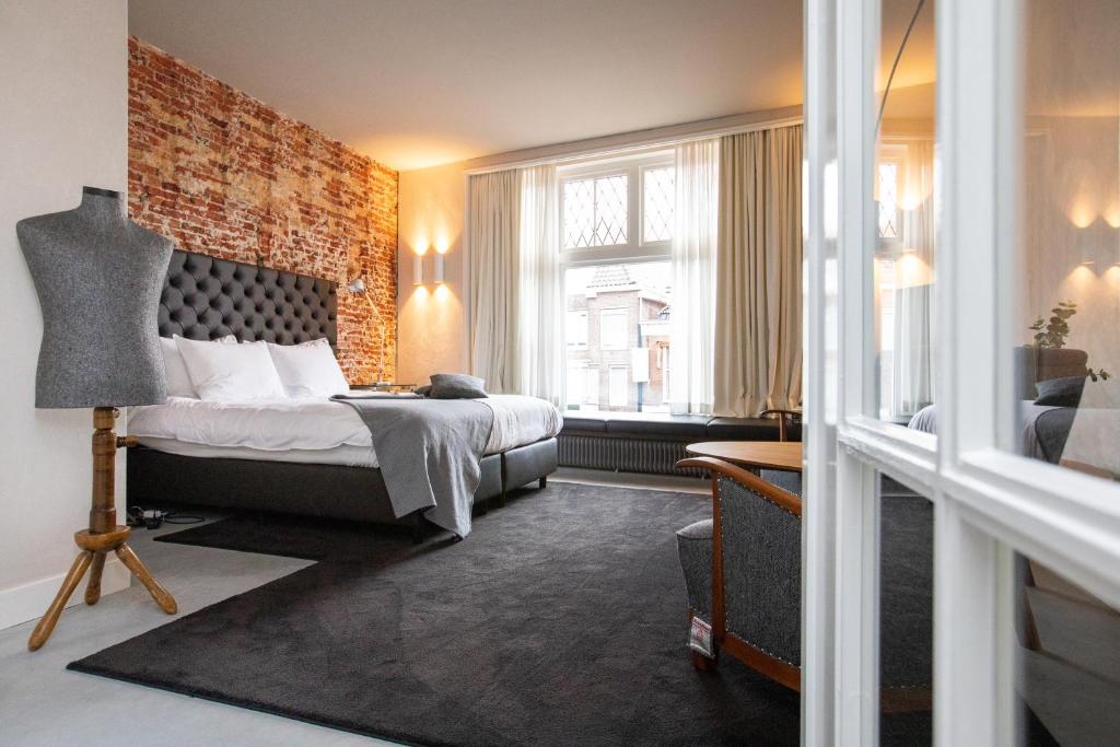 a bedroom with a bed and a brick wall at Van der Gang Suites in Dokkum