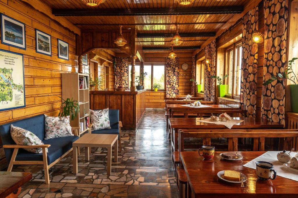 un restaurante con paredes de madera, mesas y sillas de madera en DOM NAD JEZIOREM „HUBKA”, en Maniowy