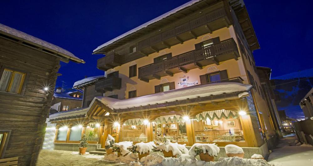 een gebouw met een winkel in de sneeuw 's nachts bij Albergo Alpenrose in Livigno