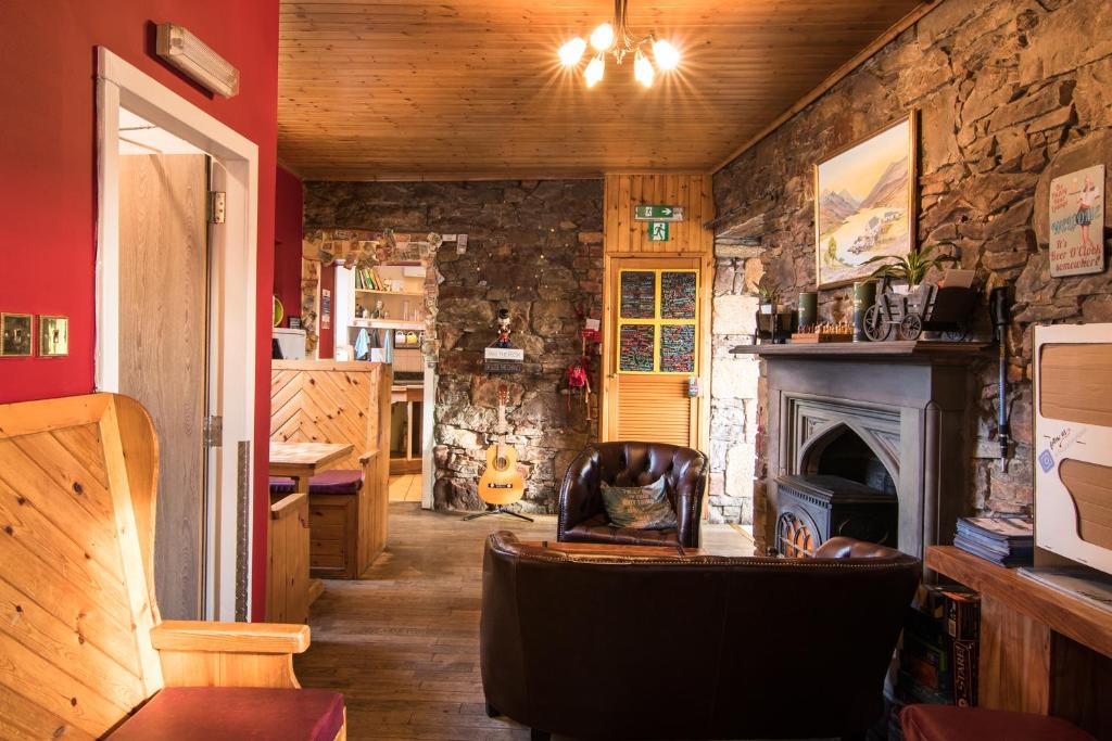 a living room with a fireplace and a stone wall at Bazpackers in Inverness