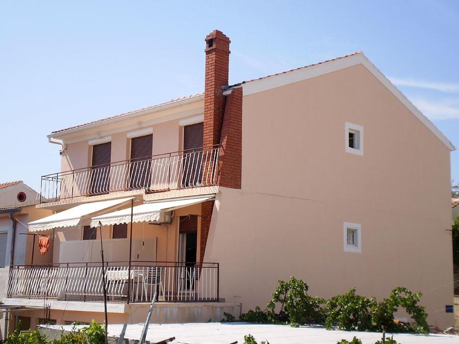 una grande casa bianca con balcone laterale di Apartments Srećko - close to center with terrace a Kukljica (Cuclizza)