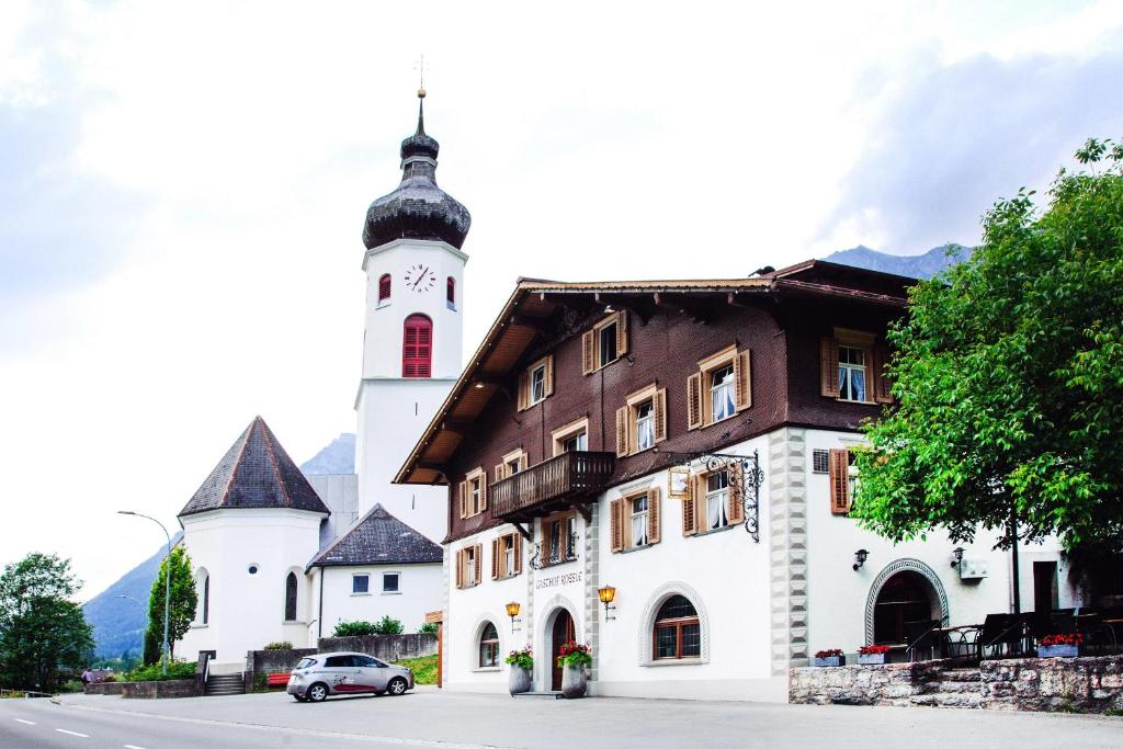 a building with a clock tower next to a street at Gasthof Rössle in Braz