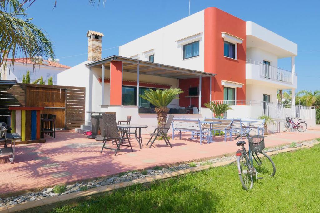 ein Haus mit einer Terrasse mit Tischen und Stühlen in der Unterkunft House of Nissus Hostel in Ayia Napa